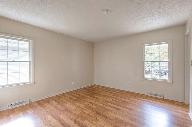 spare room with a textured ceiling and light hardwood / wood-style flooring