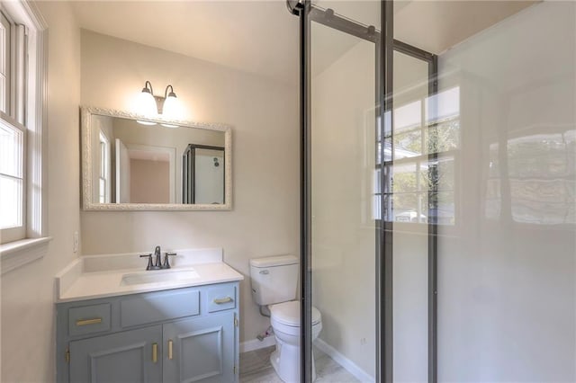 bathroom featuring toilet, vanity, and a shower with door