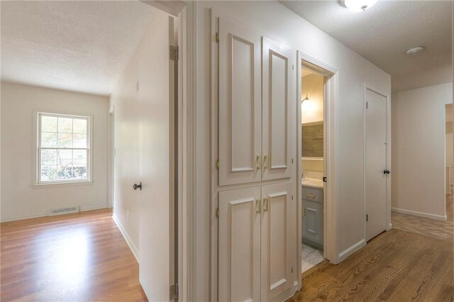 hall featuring light hardwood / wood-style floors and a textured ceiling