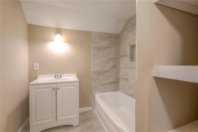 bathroom with vanity, vaulted ceiling, and a bathtub