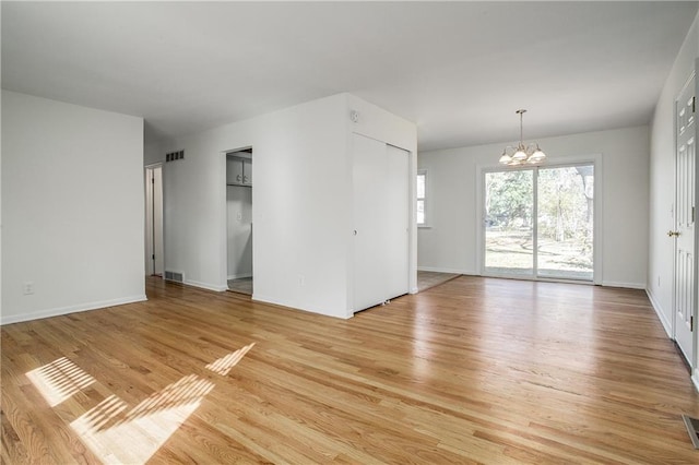 spare room with light hardwood / wood-style floors and a notable chandelier