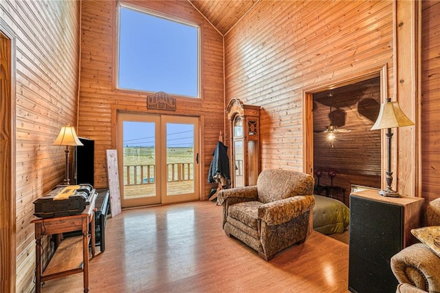 sitting room featuring french doors, wooden walls, wooden ceiling, light wood-type flooring, and high vaulted ceiling