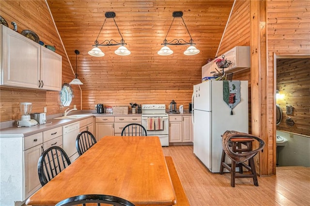 kitchen with light hardwood / wood-style flooring, pendant lighting, white appliances, and wood walls