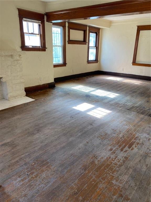 empty room with a wealth of natural light and dark hardwood / wood-style flooring