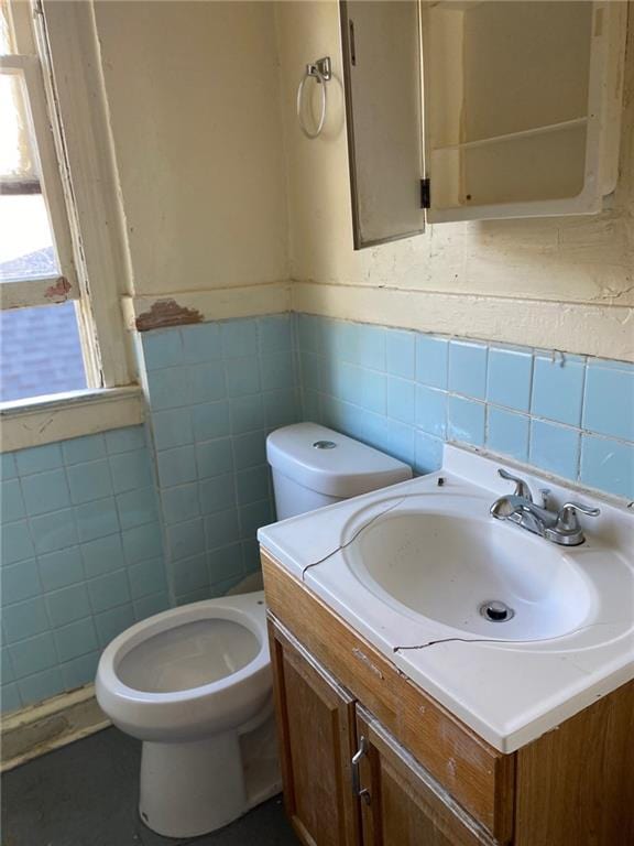 bathroom with vanity, toilet, and tile walls