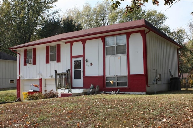 raised ranch featuring cooling unit and a front lawn