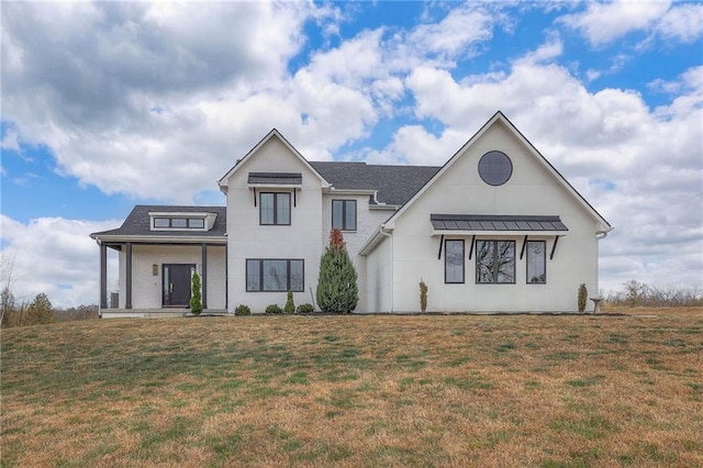 modern farmhouse featuring a porch, a front yard, and a standing seam roof