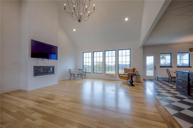 living room featuring light wood finished floors, a high ceiling, a glass covered fireplace, and recessed lighting