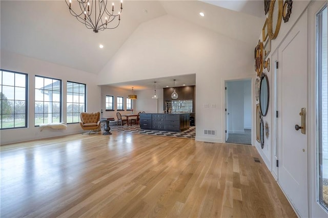 living room with a notable chandelier, recessed lighting, visible vents, light wood-style flooring, and high vaulted ceiling