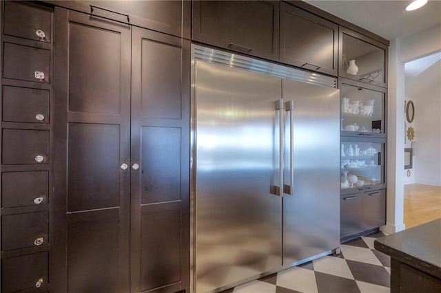 kitchen with light floors, dark brown cabinets, and built in fridge