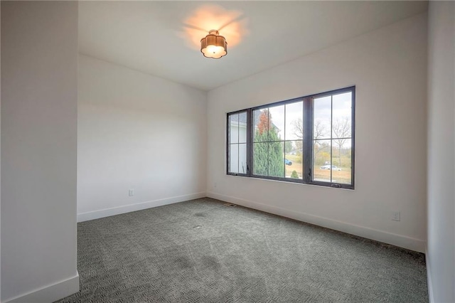 carpeted empty room featuring baseboards