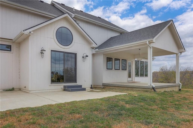 back of property featuring covered porch, a patio area, a lawn, and roof with shingles