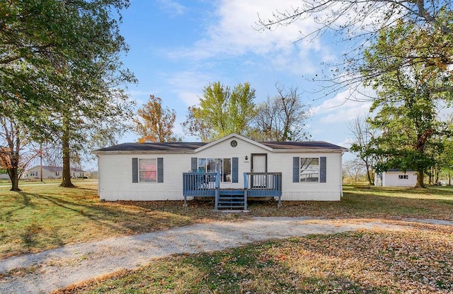 view of front facade with a shed, a front lawn, and a wooden deck