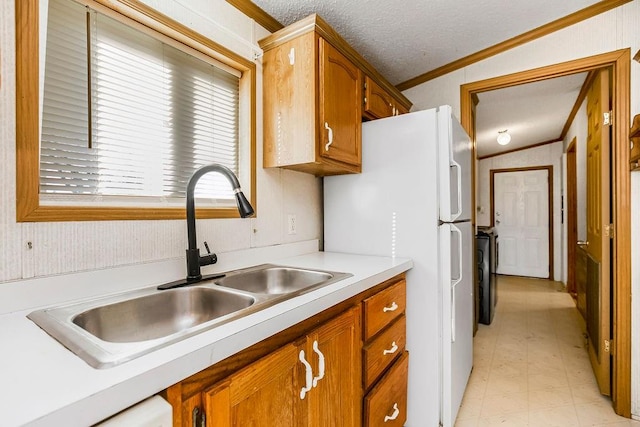 kitchen with lofted ceiling, a textured ceiling, crown molding, sink, and white refrigerator