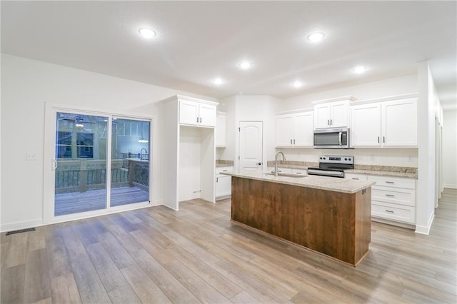 kitchen with light hardwood / wood-style floors, stainless steel appliances, a center island with sink, and sink