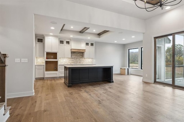 kitchen with a large island, white cabinets, backsplash, and light hardwood / wood-style floors