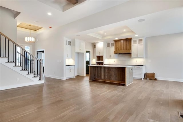 kitchen featuring a kitchen island, white cabinetry, a tray ceiling, and light hardwood / wood-style floors