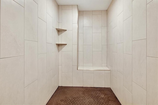 bathroom with a tile shower and tile patterned flooring