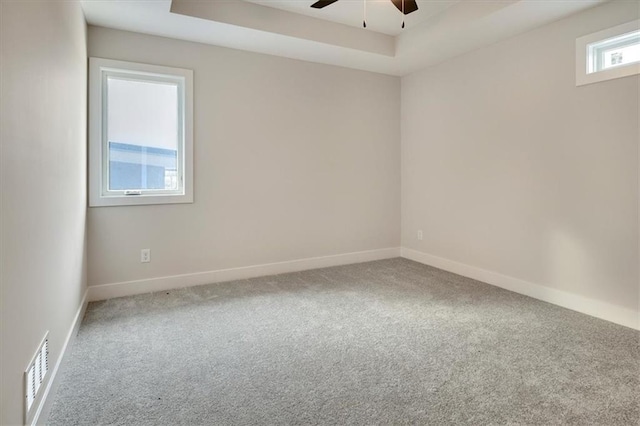 carpeted empty room with a tray ceiling and ceiling fan