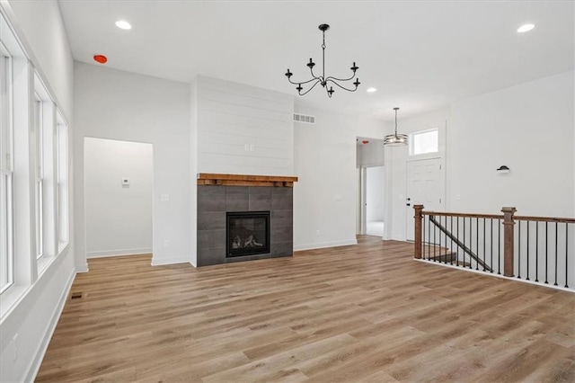 unfurnished living room featuring a notable chandelier, light hardwood / wood-style flooring, and a fireplace