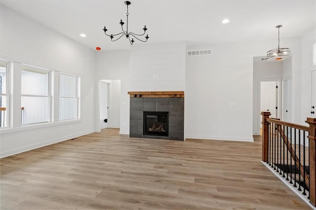 unfurnished living room featuring light hardwood / wood-style floors, a chandelier, and a fireplace