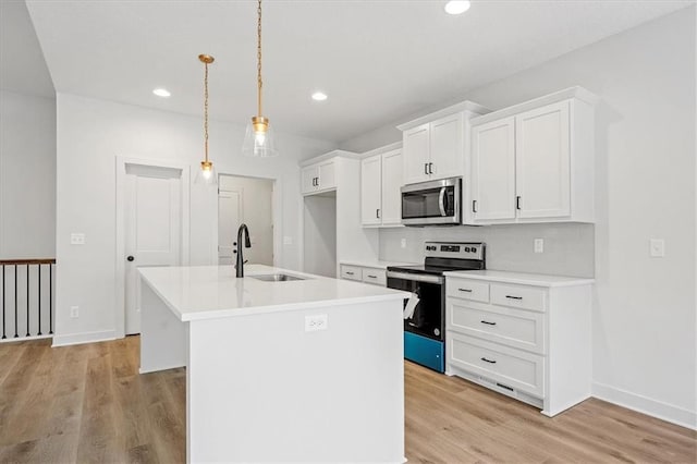 kitchen with white cabinets, hanging light fixtures, a center island with sink, appliances with stainless steel finishes, and sink