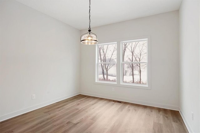 spare room with a notable chandelier and light hardwood / wood-style floors