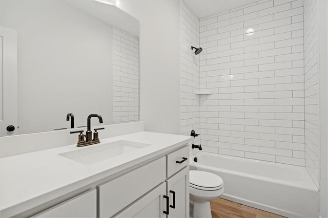 full bathroom featuring tiled shower / bath, vanity, hardwood / wood-style floors, and toilet