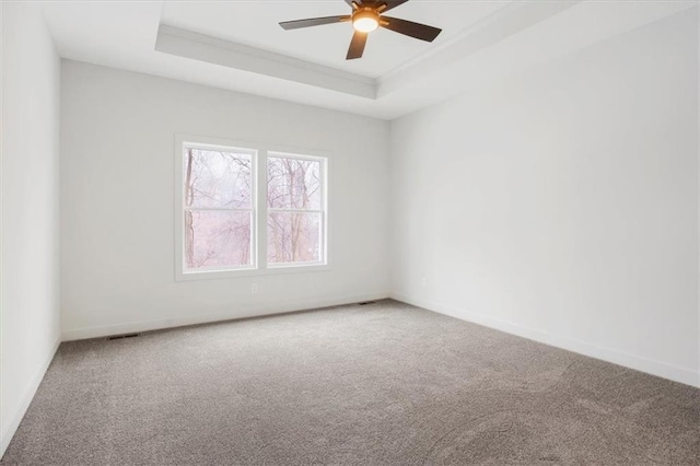 carpeted empty room with ceiling fan and a raised ceiling