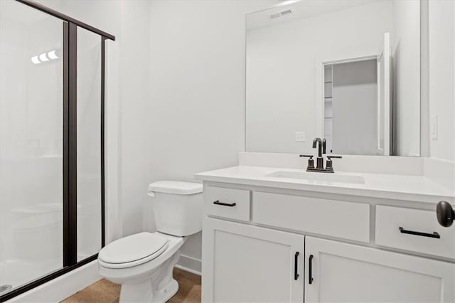 bathroom featuring vanity, a shower with shower door, and toilet