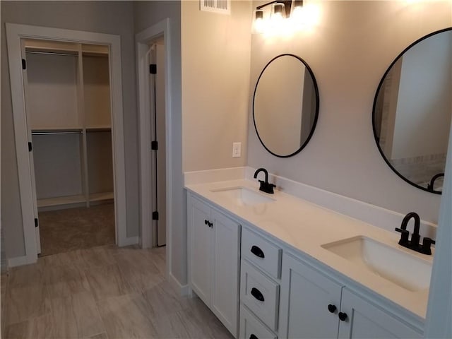 bathroom with a spacious closet, double vanity, a sink, and visible vents