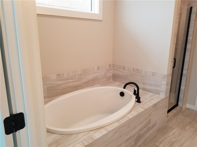 bathroom featuring a garden tub and a shower stall