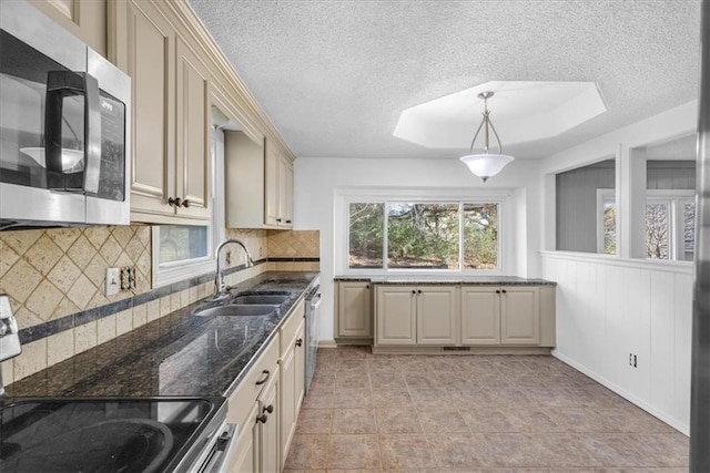 kitchen featuring backsplash, stainless steel appliances, sink, cream cabinets, and pendant lighting