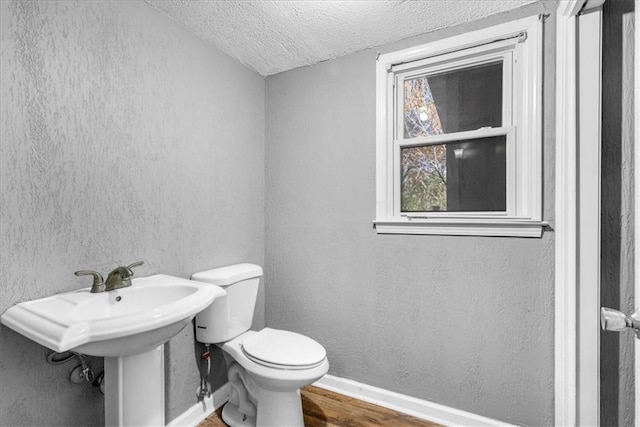 bathroom with a textured ceiling, hardwood / wood-style flooring, and toilet