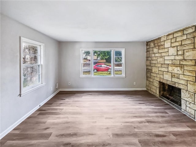 unfurnished living room with a stone fireplace and dark hardwood / wood-style flooring