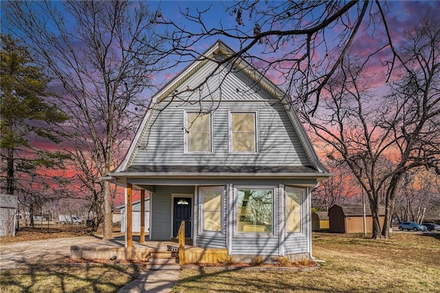 bungalow featuring a yard, a shed, and a porch