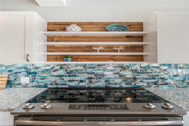 interior details with stainless steel range, white cabinetry, tasteful backsplash, and light stone counters