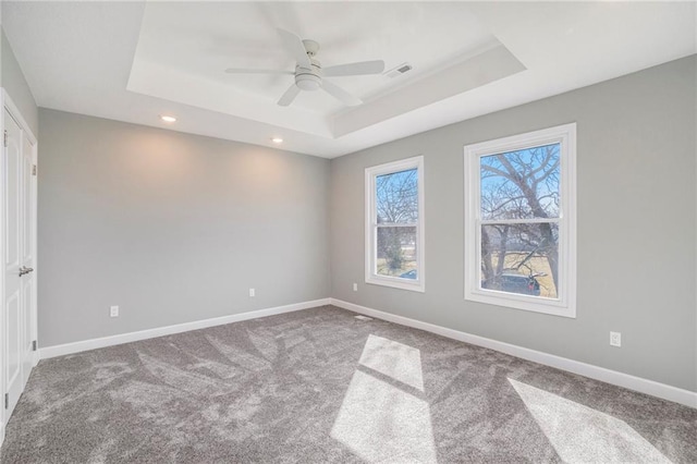 carpeted spare room with ceiling fan and a tray ceiling