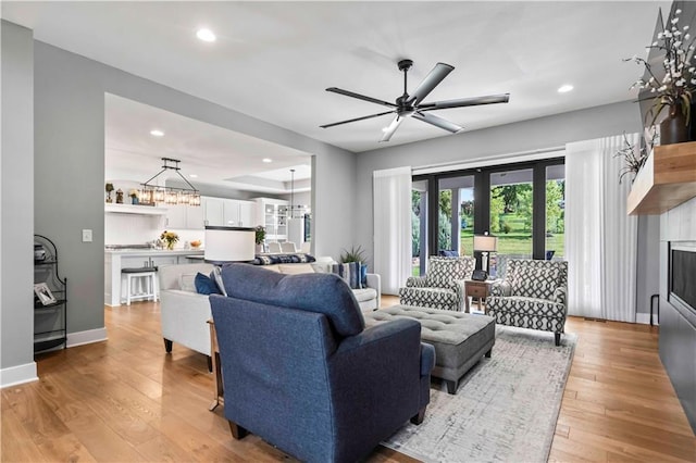 living room featuring light wood-type flooring and ceiling fan with notable chandelier