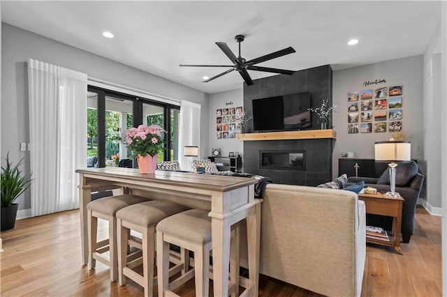 living room with ceiling fan, light wood-type flooring, and a fireplace