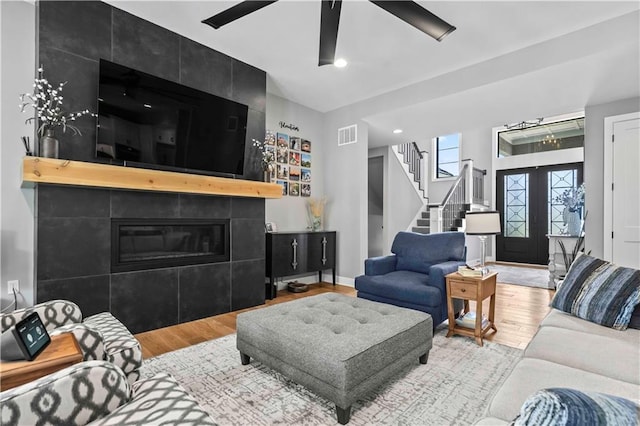 living room with ceiling fan, hardwood / wood-style floors, and a tile fireplace