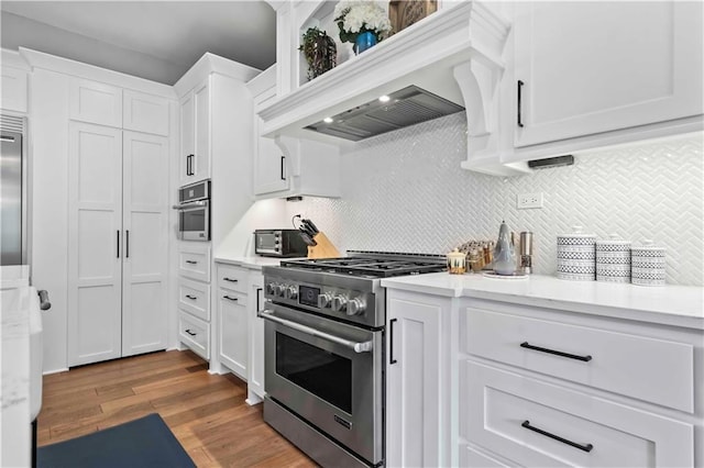 kitchen featuring white cabinets, light hardwood / wood-style floors, backsplash, premium range hood, and appliances with stainless steel finishes