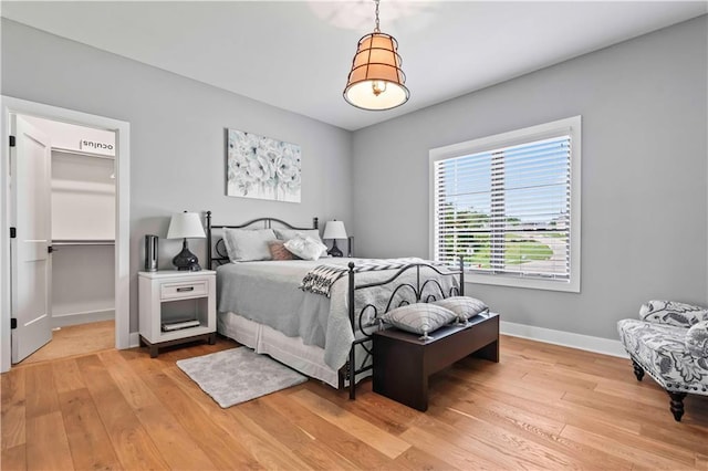 bedroom featuring a spacious closet and light hardwood / wood-style flooring