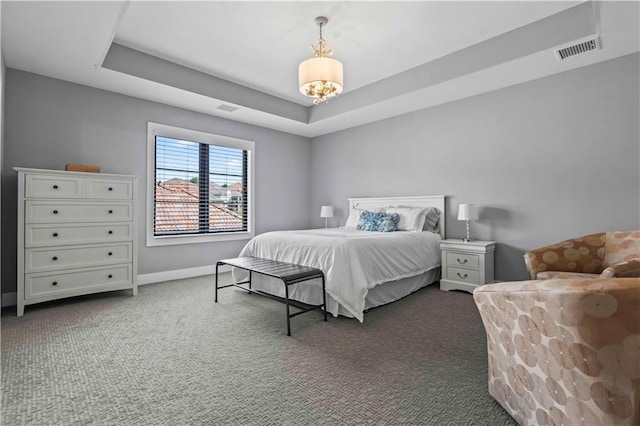 bedroom with a notable chandelier, a raised ceiling, and dark colored carpet