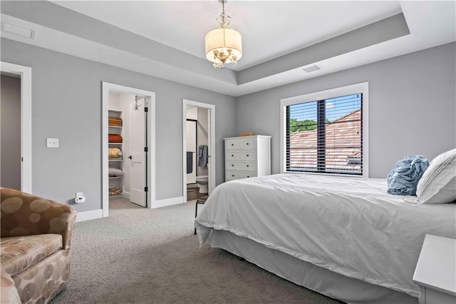 bedroom with a walk in closet, carpet floors, connected bathroom, and a tray ceiling