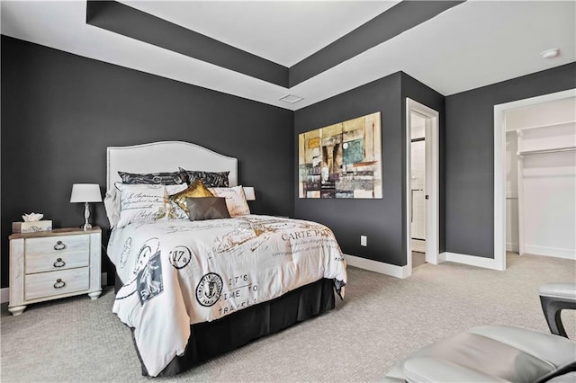 bedroom with carpet flooring, a closet, a raised ceiling, and a spacious closet