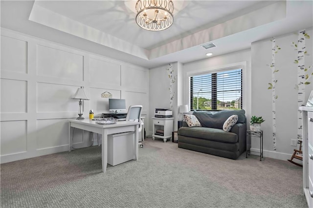 office featuring a raised ceiling, light colored carpet, and a notable chandelier