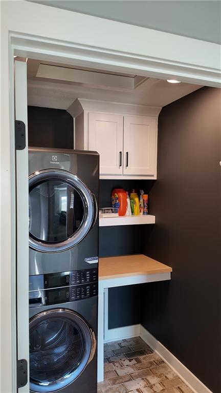 laundry area featuring cabinets and stacked washer / drying machine