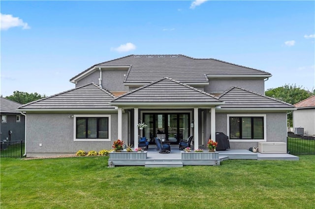 back of property featuring a wooden deck, central air condition unit, and a lawn