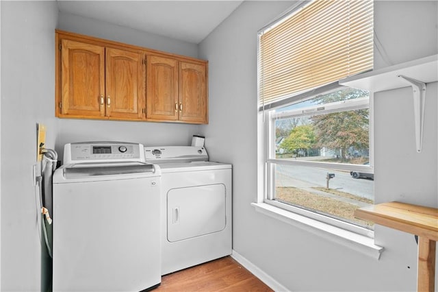 clothes washing area with light hardwood / wood-style floors, cabinets, and separate washer and dryer